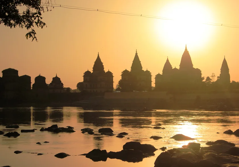 The royal chhatris of Orchha silhouetted against sunset on the Betwa river